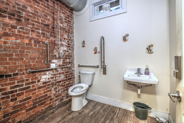 bathroom featuring hardwood / wood-style flooring, brick wall, sink, and toilet