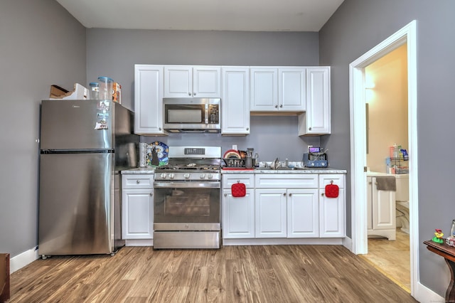 kitchen featuring appliances with stainless steel finishes, sink, white cabinets, and light hardwood / wood-style flooring