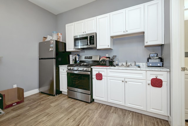 kitchen featuring stainless steel appliances, light hardwood / wood-style floors, sink, and white cabinets