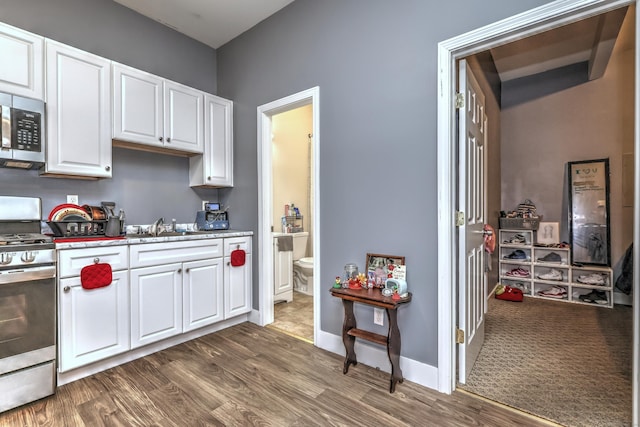 kitchen with white cabinetry, stainless steel appliances, and dark hardwood / wood-style flooring