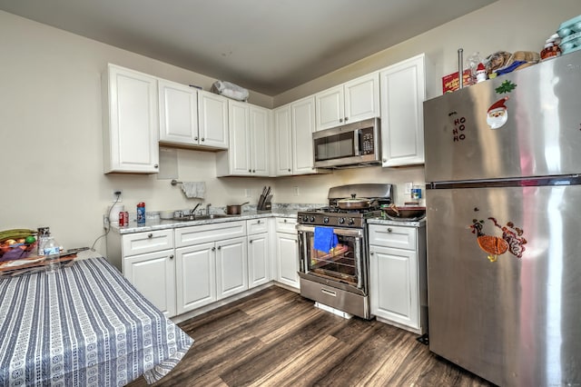 kitchen with appliances with stainless steel finishes, stone countertops, dark hardwood / wood-style floors, sink, and white cabinets