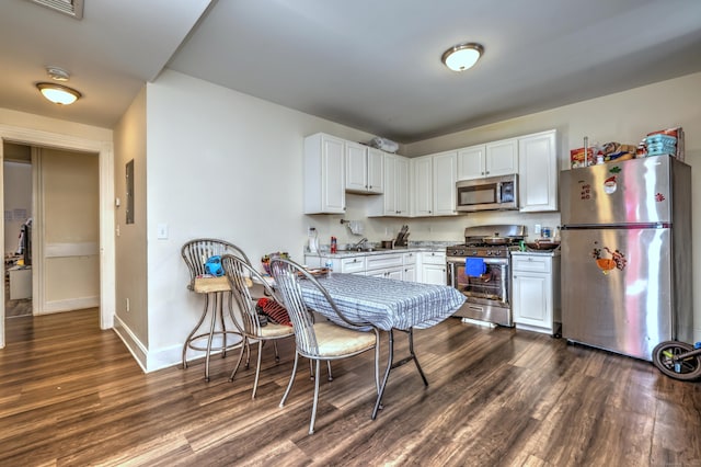 kitchen with stainless steel appliances, white cabinetry, and dark wood-type flooring