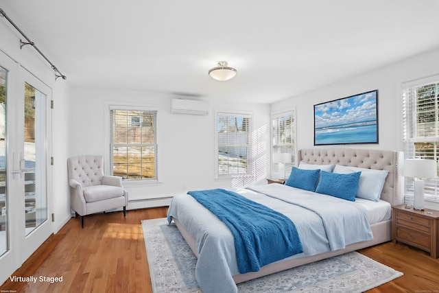 bedroom featuring a wall mounted air conditioner, light hardwood / wood-style floors, and access to exterior