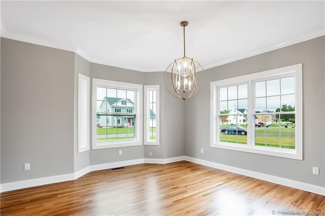 spare room with ornamental molding, light hardwood / wood-style floors, and a chandelier