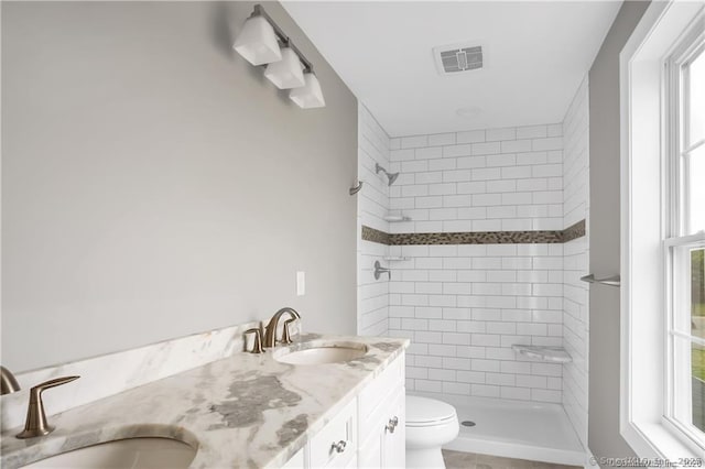 bathroom with vanity, tiled shower, and toilet