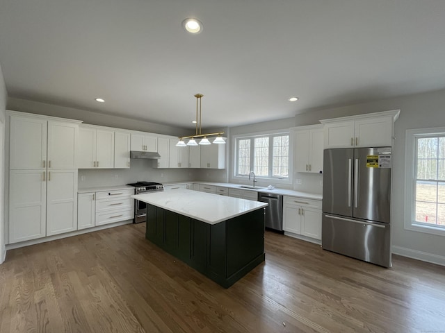 kitchen featuring sink, white cabinetry, a center island, appliances with stainless steel finishes, and pendant lighting