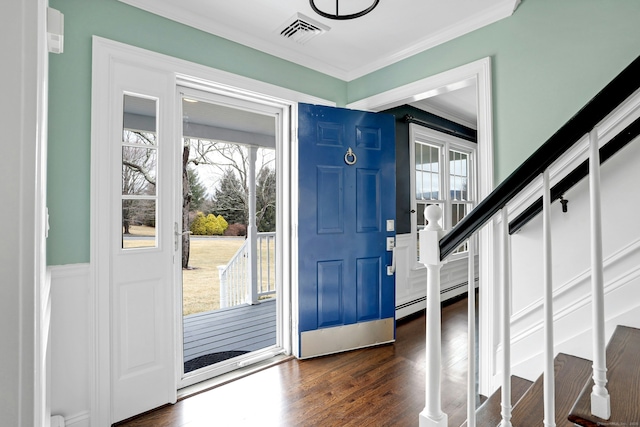 foyer entrance featuring dark wood finished floors, crown molding, a baseboard radiator, visible vents, and stairs