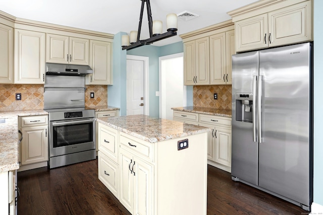 kitchen with visible vents, dark wood-type flooring, cream cabinets, stainless steel appliances, and under cabinet range hood