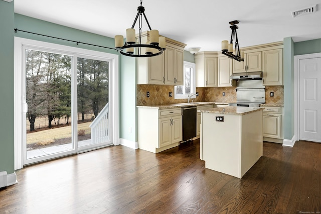 kitchen featuring under cabinet range hood, a chandelier, cream cabinetry, and dishwasher