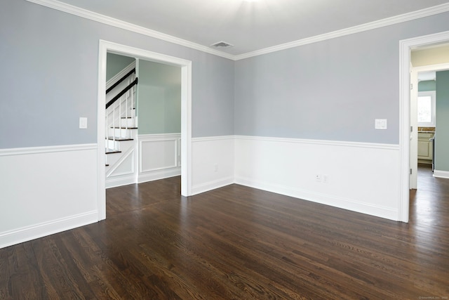 empty room with a wainscoted wall, visible vents, dark wood-type flooring, ornamental molding, and stairs