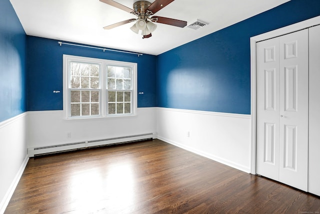 unfurnished bedroom featuring a closet, a baseboard radiator, wood finished floors, and visible vents