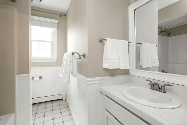 full bathroom with tile patterned floors, vanity, a baseboard heating unit, and wainscoting