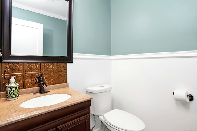 half bathroom featuring toilet, decorative backsplash, crown molding, and vanity