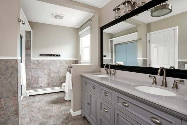 full bath featuring toilet, a sink, tile walls, and baseboard heating