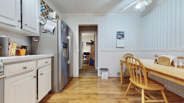 kitchen featuring stainless steel fridge, white cabinets, ornamental molding, ceiling fan, and light hardwood / wood-style flooring