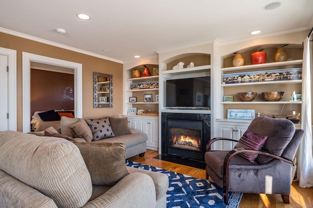 living room with built in shelves, ornamental molding, and light hardwood / wood-style floors