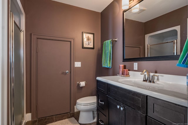 bathroom featuring a shower with door, vanity, tile patterned floors, and toilet