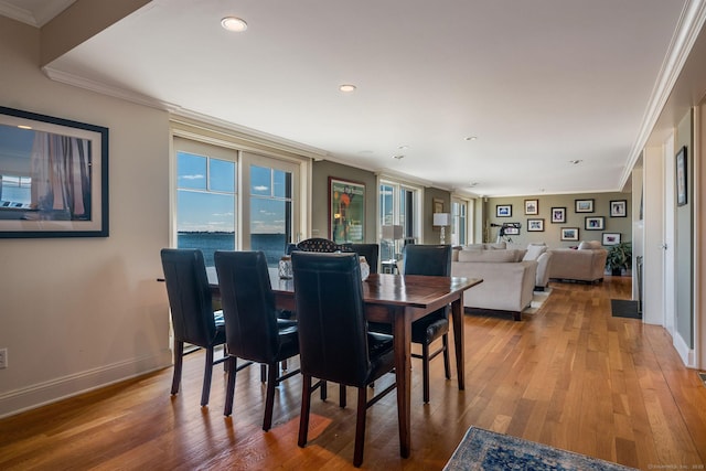 dining space featuring hardwood / wood-style floors, ornamental molding, and a water view