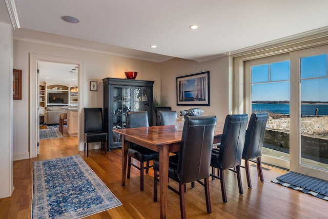 dining area featuring crown molding, a water view, and hardwood / wood-style floors