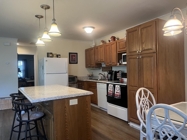 kitchen with sink, a center island, dark hardwood / wood-style floors, pendant lighting, and white appliances