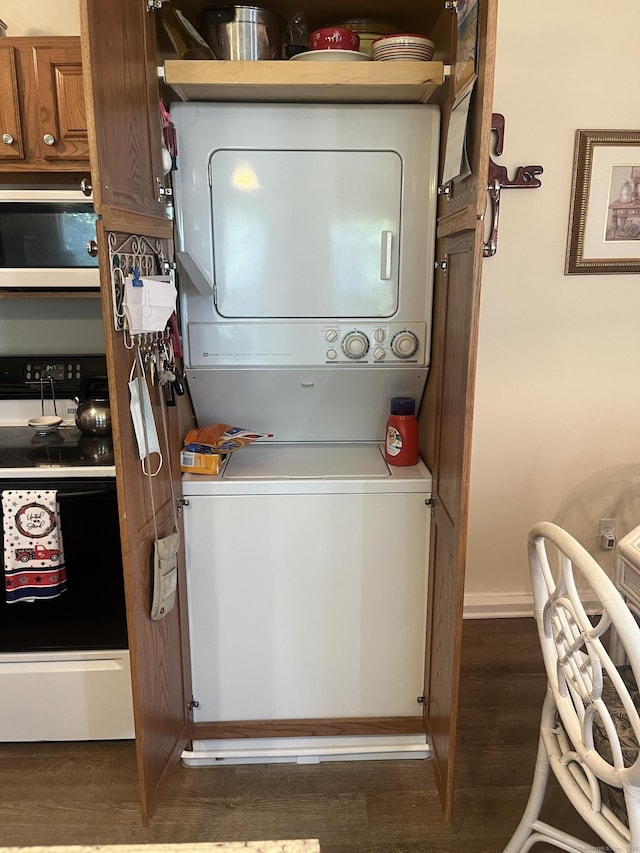 laundry area featuring stacked washer / dryer and dark wood-type flooring