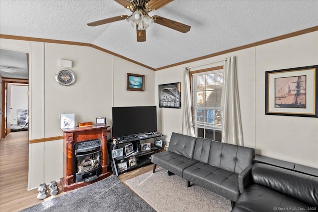 living room featuring ceiling fan, ornamental molding, a textured ceiling, vaulted ceiling, and light wood-type flooring