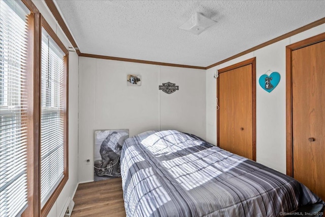 bedroom with hardwood / wood-style flooring, ornamental molding, and a textured ceiling