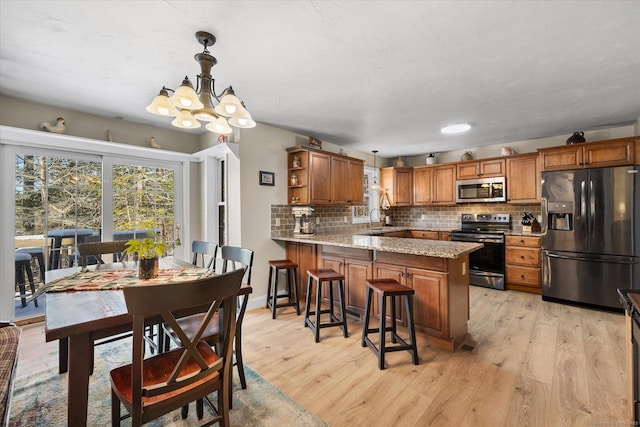 kitchen with pendant lighting, stainless steel appliances, kitchen peninsula, and sink