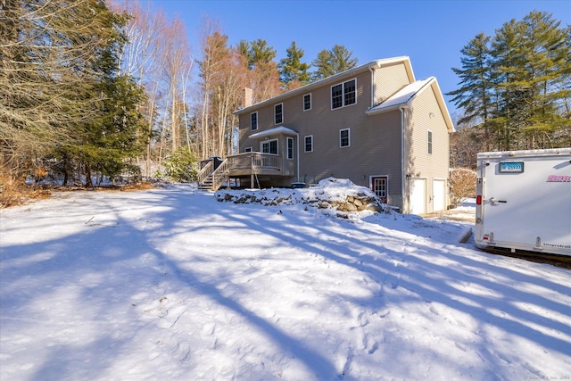 snow covered back of property with a deck