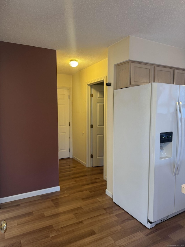 kitchen featuring dark wood-type flooring, a textured ceiling, light brown cabinets, and white fridge with ice dispenser