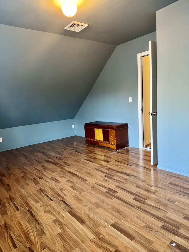 additional living space featuring lofted ceiling and light hardwood / wood-style flooring