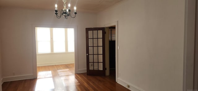 spare room with ornamental molding, dark hardwood / wood-style floors, and a notable chandelier