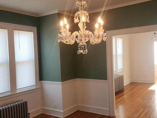 unfurnished dining area featuring an inviting chandelier, hardwood / wood-style flooring, and radiator heating unit