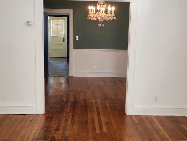 unfurnished dining area featuring an inviting chandelier and dark hardwood / wood-style flooring