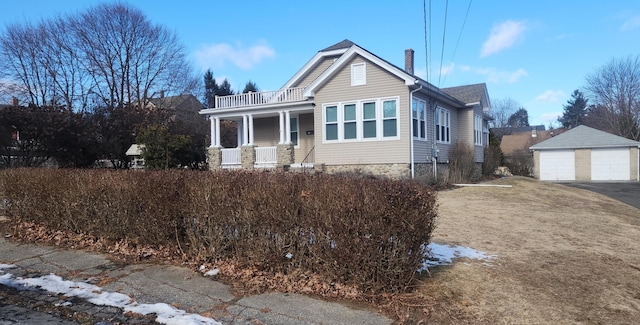 view of front of property with a garage, a balcony, a porch, and an outbuilding