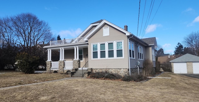 view of front of property with a garage, an outdoor structure, a porch, and a front lawn