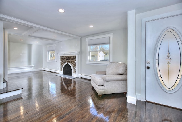 living room featuring baseboard heating, a fireplace, and dark wood-type flooring