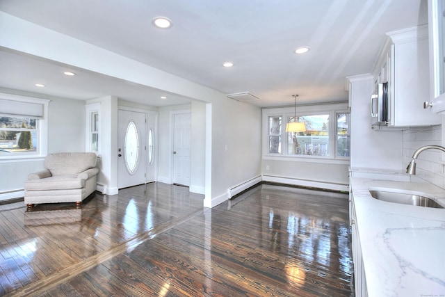 interior space with dark wood-type flooring, plenty of natural light, sink, and a baseboard heating unit