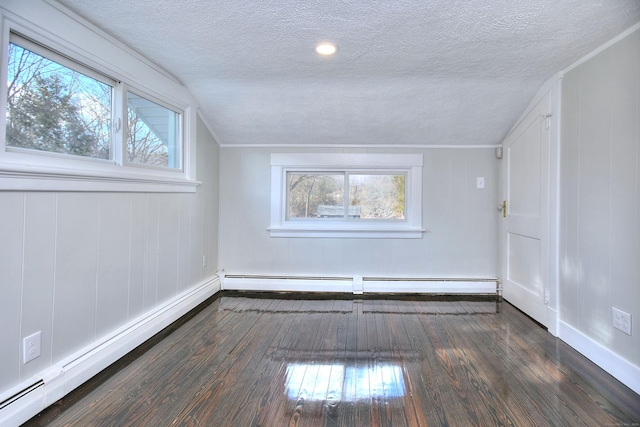 spare room with dark wood-type flooring, a baseboard radiator, and a textured ceiling