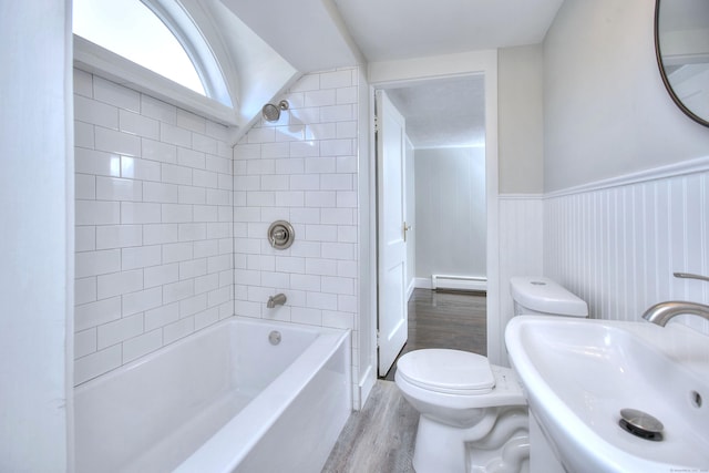 full bathroom featuring toilet, sink, baseboard heating, tiled shower / bath combo, and hardwood / wood-style flooring