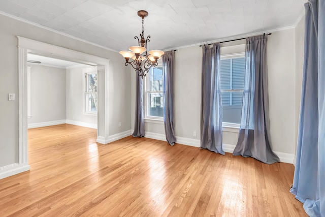 unfurnished room featuring an inviting chandelier, crown molding, and light hardwood / wood-style floors