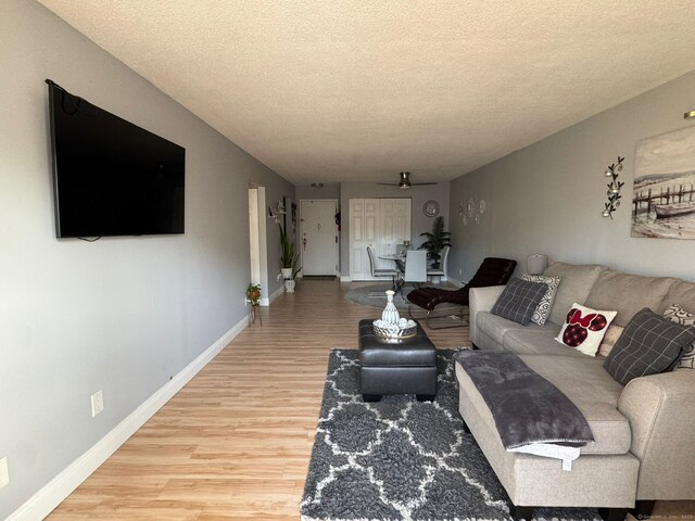 living room with ceiling fan, hardwood / wood-style floors, and a textured ceiling