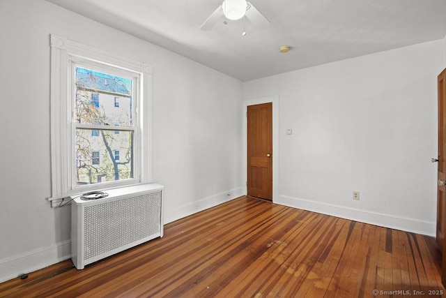 spare room featuring hardwood / wood-style floors, radiator heating unit, and ceiling fan