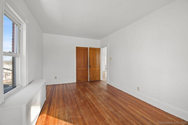 unfurnished room featuring wood-type flooring and radiator