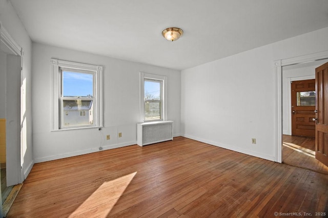 unfurnished room with hardwood / wood-style floors and radiator heating unit