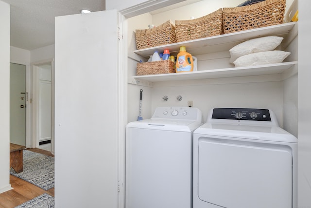 washroom with washing machine and dryer, hardwood / wood-style floors, and a textured ceiling