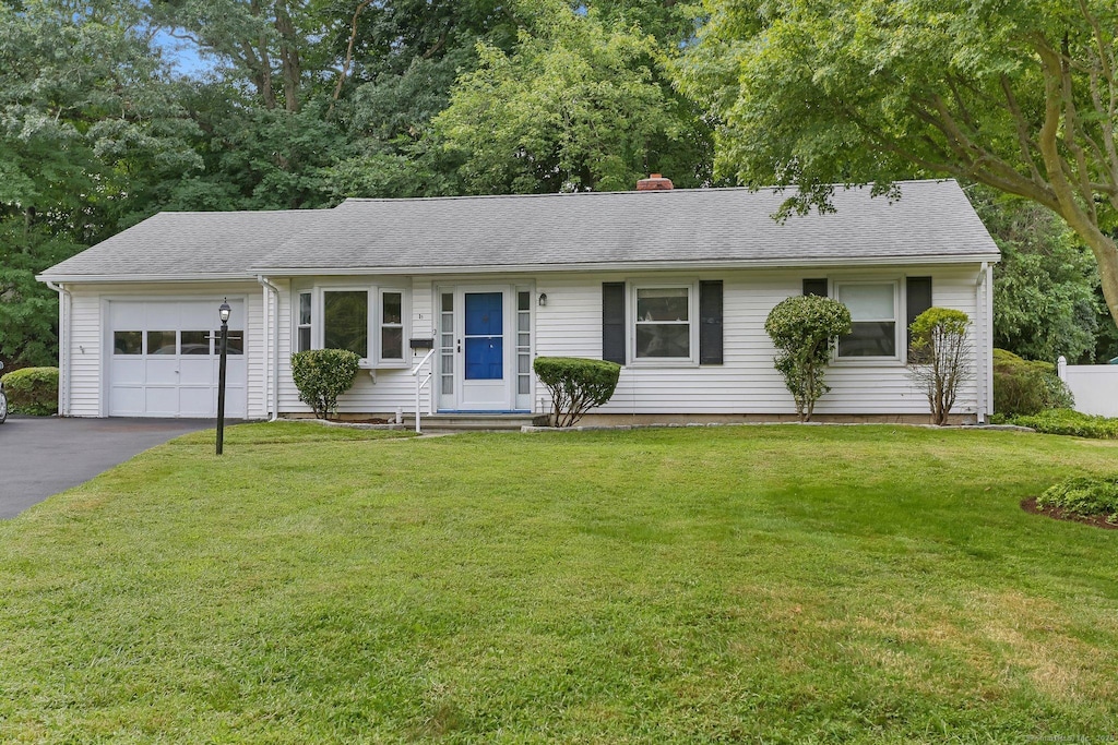 ranch-style home featuring a garage and a front lawn