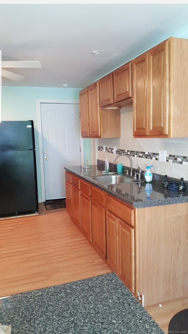 kitchen with black refrigerator, sink, decorative backsplash, and light wood-type flooring