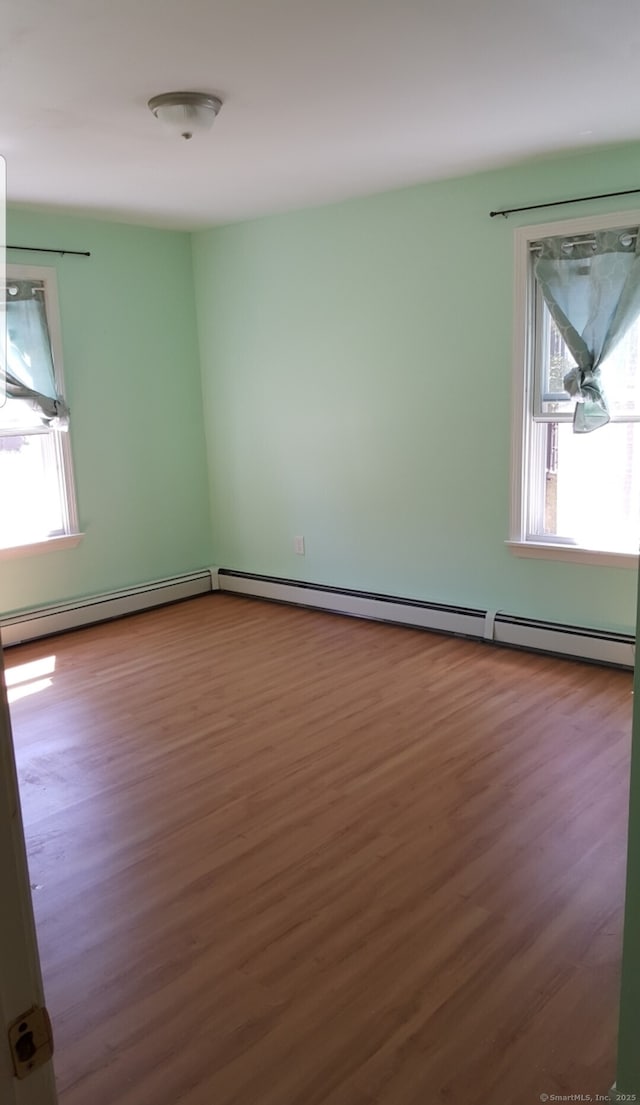 spare room featuring hardwood / wood-style floors, plenty of natural light, and baseboard heating