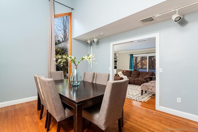 dining area with hardwood / wood-style floors and track lighting